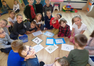 Dzieci oglądają przykładowe ilustracje śladów zwierząt